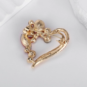 Golden heart rhinestone brooch featuring safety pin back on light gray background