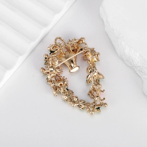 Elegante goldene Blumenkorb-Brosche mit sicherem Nadelverschluss auf Steinhintergrund