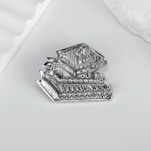 Silver book-shaped rhinestone brooch back view with safety pin on textured base