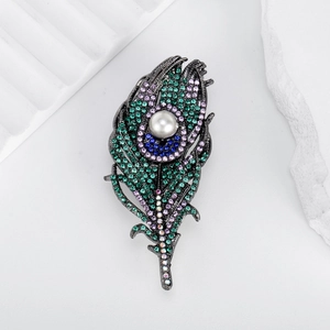 Exquisite peacock feather brooch with colorful crystals and pearl on a white background
