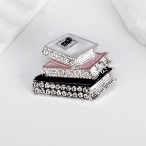 Exquisite stacked books enamel brooch with clear rhinestones on a white background
