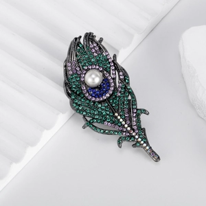 Exquisite peacock feather brooch with pearls and colorful crystals on stone display