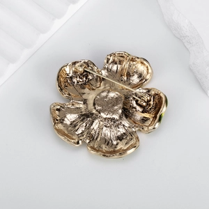 Vue arrière de la broche fleur vintage dorée avec émail vert et fermoir épingle de sûreté