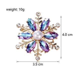 Broche flocon de neige dorée avec pierres violettes dégradées et perle centrale