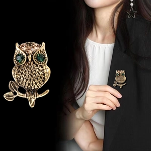 Vintage owl brooch in antique gold finish with green crystal eyes on black suit lapel