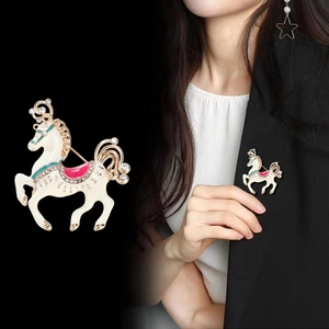 Creative white enamel horse brooch with pink saddle and rhinestones on a blazer