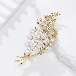 Élégante broche d'épi de blé dorée avec perles et cristaux sur fond de pierre blanche