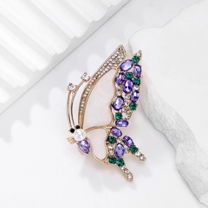 Elegant butterfly brooch with purple stones and pearl on a white textured background
