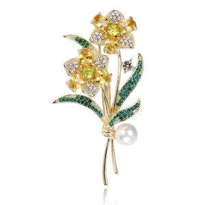 Elegante broche de rosa con cristales amarillos, hojas verdes y perla blanca en fondo blanco