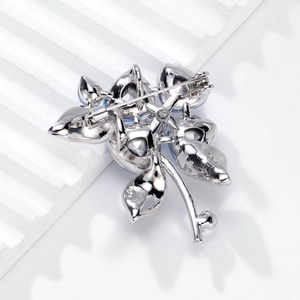 Silver crystal flower brooch with blue stones shown from a back view with safety pin