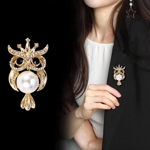 Broche hibou dorée exquise avec strass et perle sur un blazer noir élégant