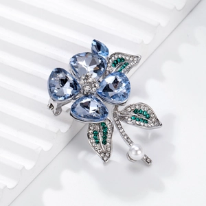 Elegant crystal flower brooch with blue petals, green leaves and a round white pearl