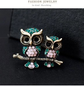 Macro shot of vintage owl brooch with emerald and pink gemstones on bronze finish