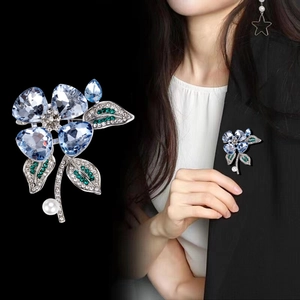 Elegant floral crystal brooch with blue heart gems and white pearl on black blazer