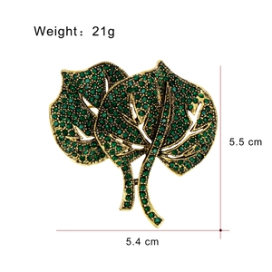 Golden leaf brooch with green rhinestones and dimensions shown on white background