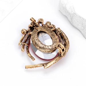 Vintage gold alloy brooch with large oval gemstone and red rhinestones on white background