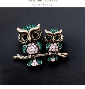 Detailed close-up of retro owl brooch featuring green rhinestones on dark leather background