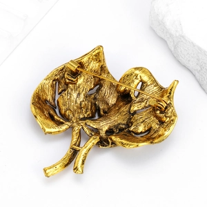 Back view of luxury gold leaf brooch with safety pin clasp on a marble stone base