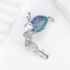 Elegant silver leaf brooch with blue rhinestones and a white pearl on a stone pedestal