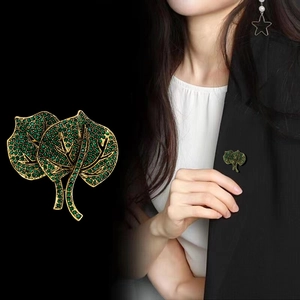 Close-up of luxury leaf brooch with emerald green rhinestones on black blazer