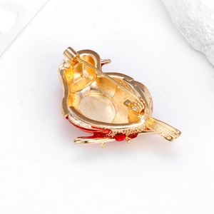 Vue arrière d'une broche oiseau en métal doré avec émail rouge et fermoir de sécurité