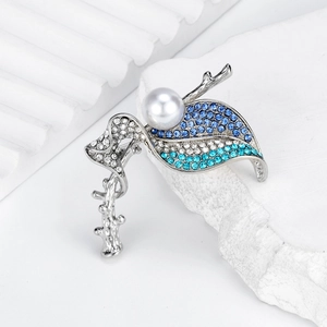 Elegant silver leaf brooch with blue rhinestones and pearl on a white background