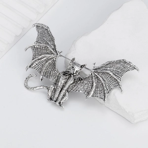 Vintage silver flying cat bat brooch with gothic alloy wings on a white stone background