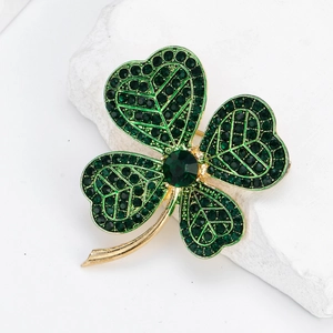 Elegante gouden klavertje vier speld met groene kristallen op witte stenen decoratie