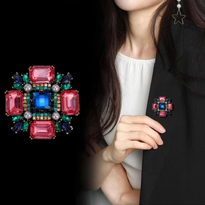 Détails de la broche rétro géométrique avec pierres colorées et perles sur un costume noir