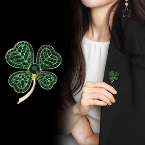 Detailweergave van klavertje vier broche met groene kristallen op een zwart jasje