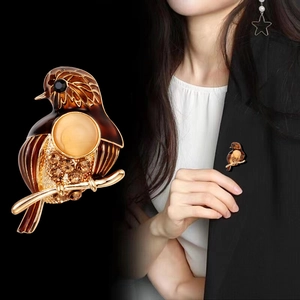 Broche pie en émail marron avec strass et pierre précieuse sur un costume noir