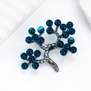 Elegant vintage tree brooch with deep blue beads on minimalist white background