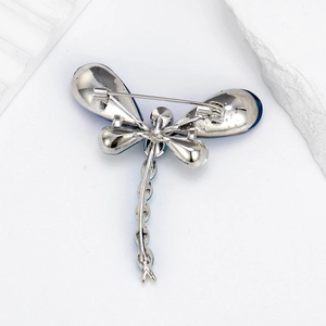 Silver dragonfly brooch with blue glass inlay showing detailed back pin and metal finish