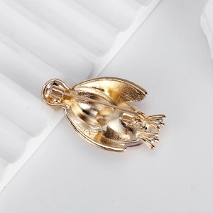 Golden penguin brooch back view with detailed pin fastener on white stone background