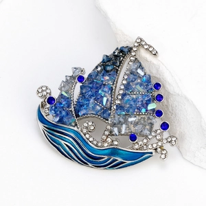 Broche de velero de lujo con cristales azules y esmalte sobre elegante fondo de piedra