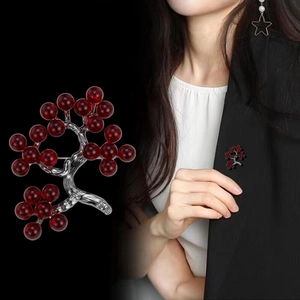 Holly berry branch brooch with red beads and silver metal frame, shown on model