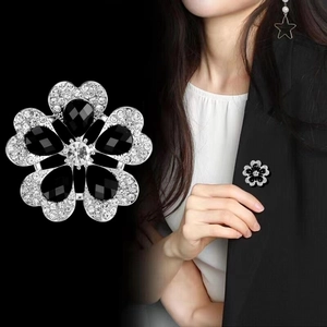 Broche fleur élégante à cinq pétales avec strass et gemmes noires sur un costume noir