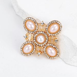 Vintage gold baroque cross brooch with pink pearls and rhinestones on a stone block