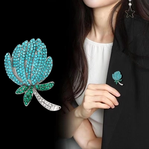 Détail d'une broche fleur en cristaux sarcelle épinglée sur le revers d'un costume noir