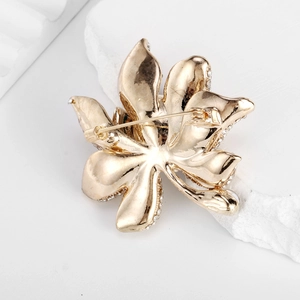 Back view of a gold flower brooch with crystals and a secure safety pin fastener