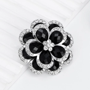 Elegant silver-toned flower brooch featuring black gemstones and sparkling rhinestones