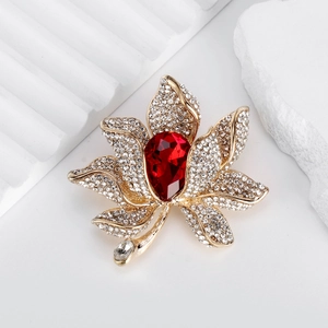 Elegant gold flower brooch with a large red teardrop gem and sparkling white crystals