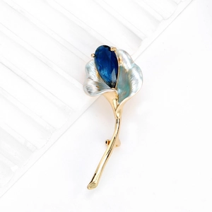 Élégante broche calla avec cristal bleu en goutte et émail blanc sur métal doré chic