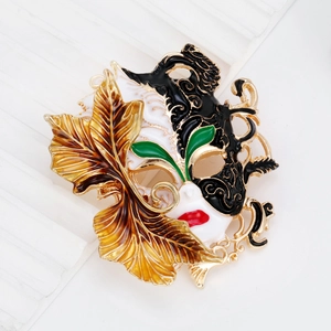 Vintage Baroque style mask brooch in gold metal with white enamel and leaf detail