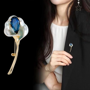 Broche calla en émail blanc et cristal bleu sur un blazer noir pour femme élégante