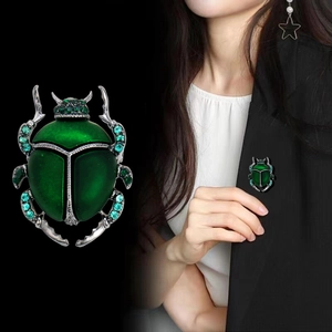 Elegante spilla a scarabeo verde con smalto e cristalli su un blazer nero da donna