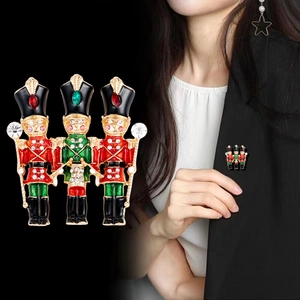 Three nutcracker soldier enamel brooches with red and green detail and gold accents