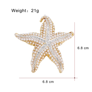 Broche étoile de mer dorée avec perles blanches et strass brillants sur fond blanc