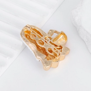 Back view of golden Halloween ghost brooch with secure pin clasp on a white stone base