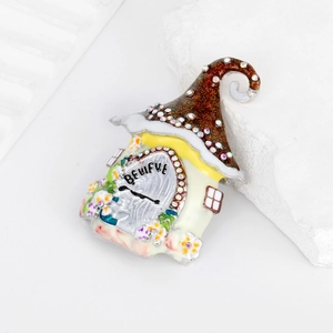 Weihnachtliche Haus-Brosche mit BELIEVE-Schriftzug und funkelnden Strasssteinen auf Stein